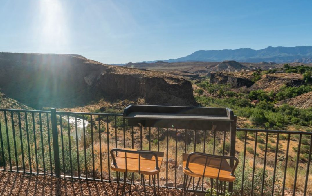 Scenic canyon view from balcony with chairs at sunrise.