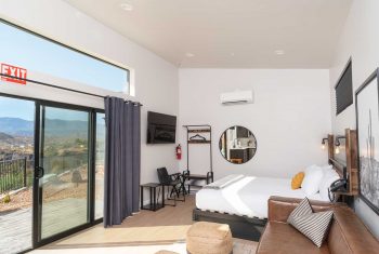 Modern hotel room with scenic mountain view through balcony.