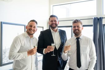 Three men toasting with champagne indoors.