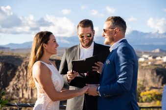 Outdoor wedding ceremony with officiant and smiling couple.