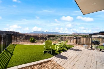 Backyard with mountain view, artificial grass, and wooden deck.
