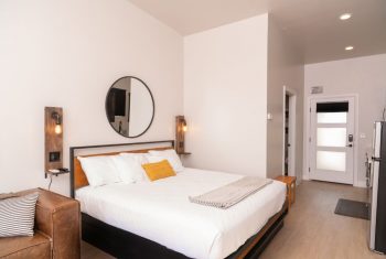 Modern minimalist hotel room interior with queen bed.
