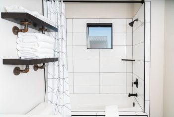 Modern bathroom with white tiles and black fixtures.