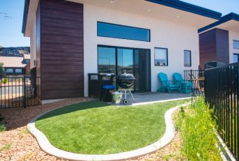 Modern home exterior with patio and barbecue grill.