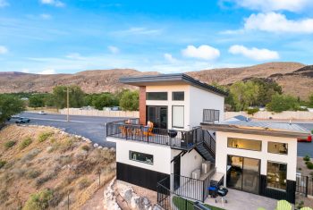 Modern house with balcony near mountain hillside.