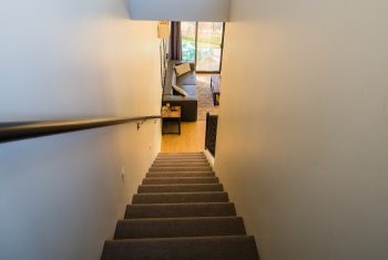Carpeted staircase leading to a furnished living room.