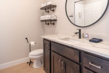 Modern bathroom with round mirror and dark wood vanity.