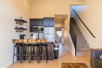 Modern kitchen interior with wooden bar stools and staircase.