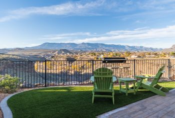 Patio with green chairs overlooking mountain landscape.