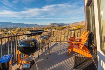 Patio with grill overlooking mountains at sunset.