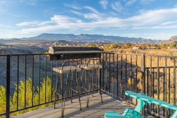 Balcony view with barbecue overlooking mountains at sunset.